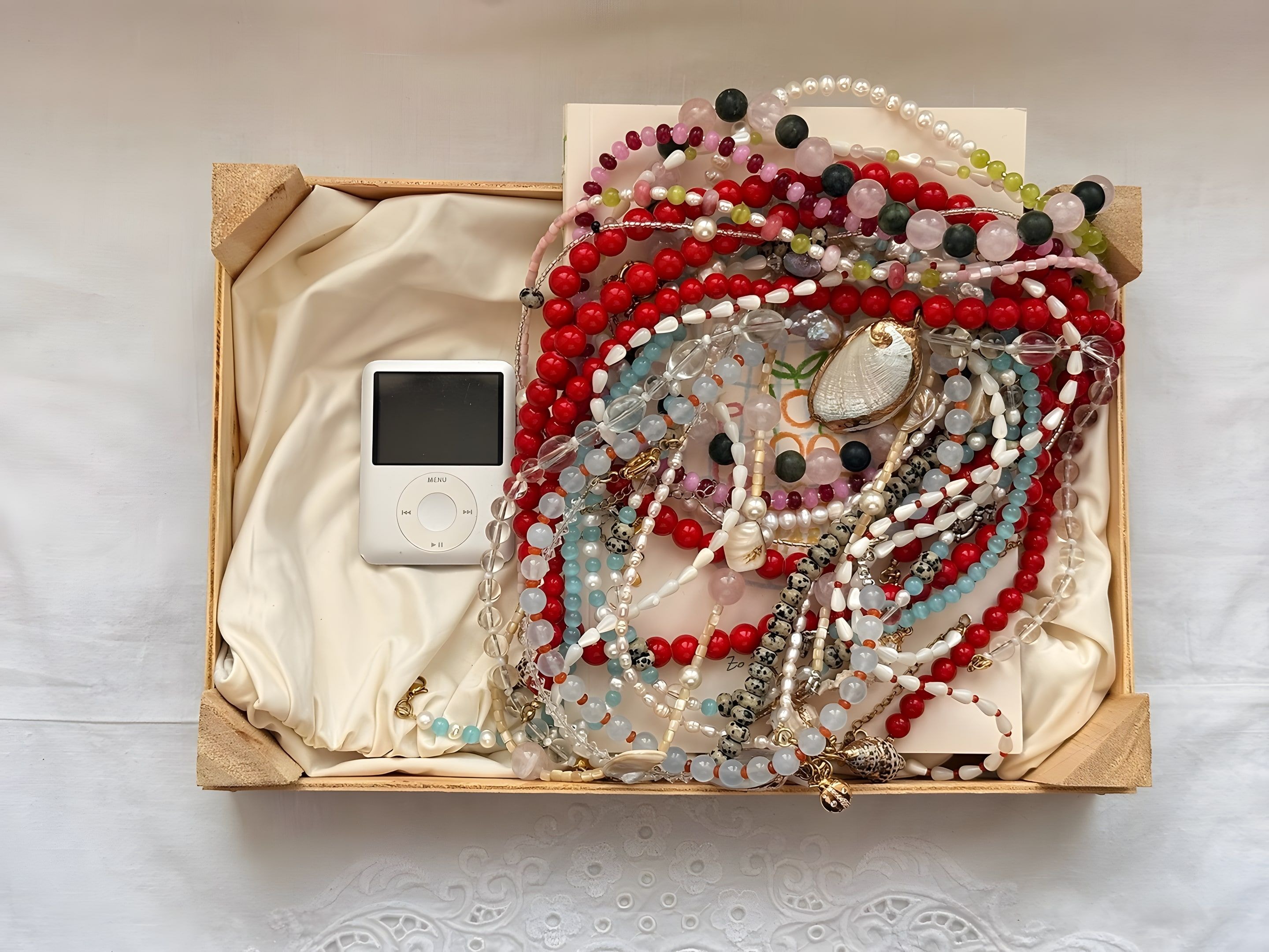 Colliers en perles multicolores présentés sur des présentoirs argentés, fond clair
