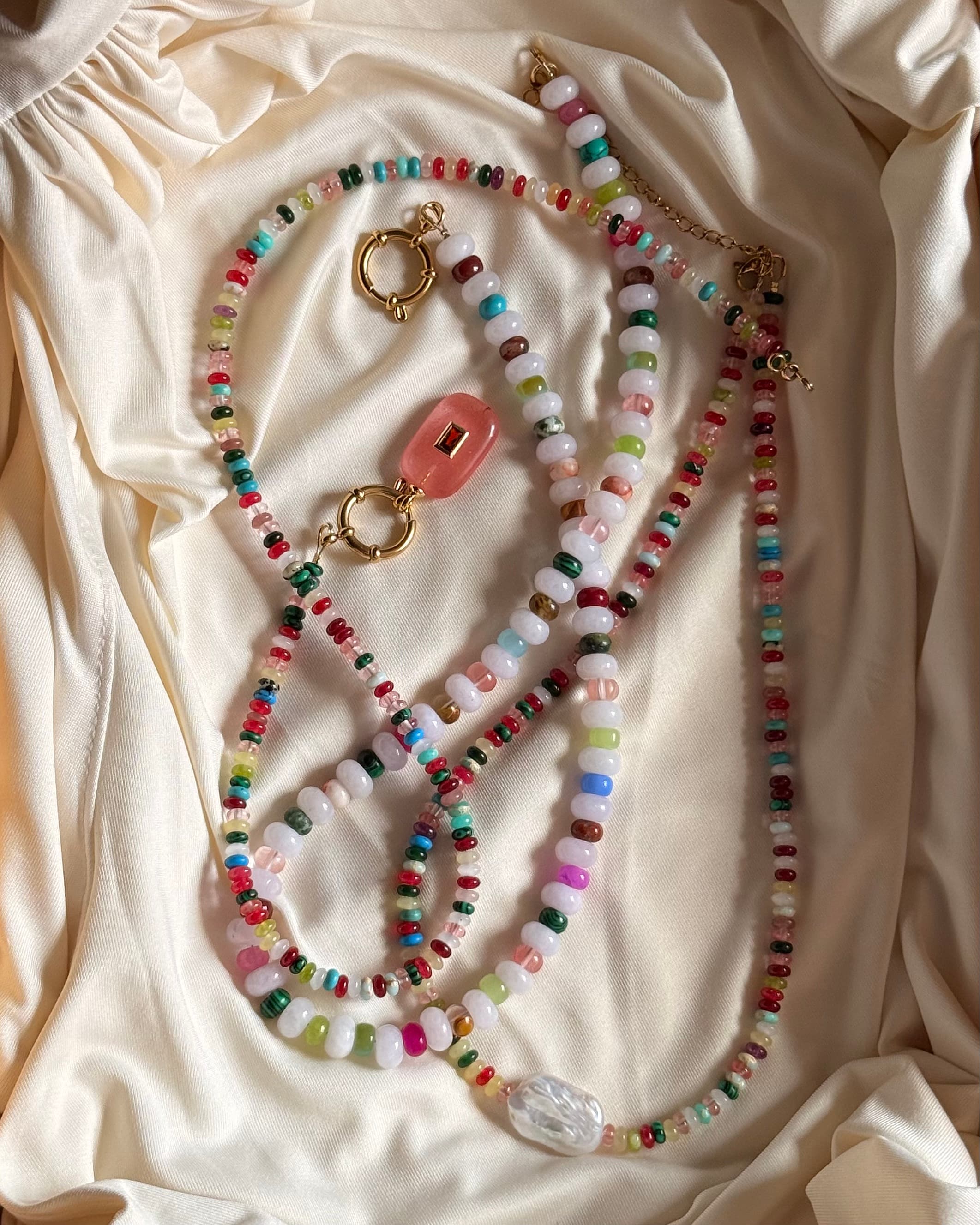 Colliers en perles multicolores posés sur soie ivoire