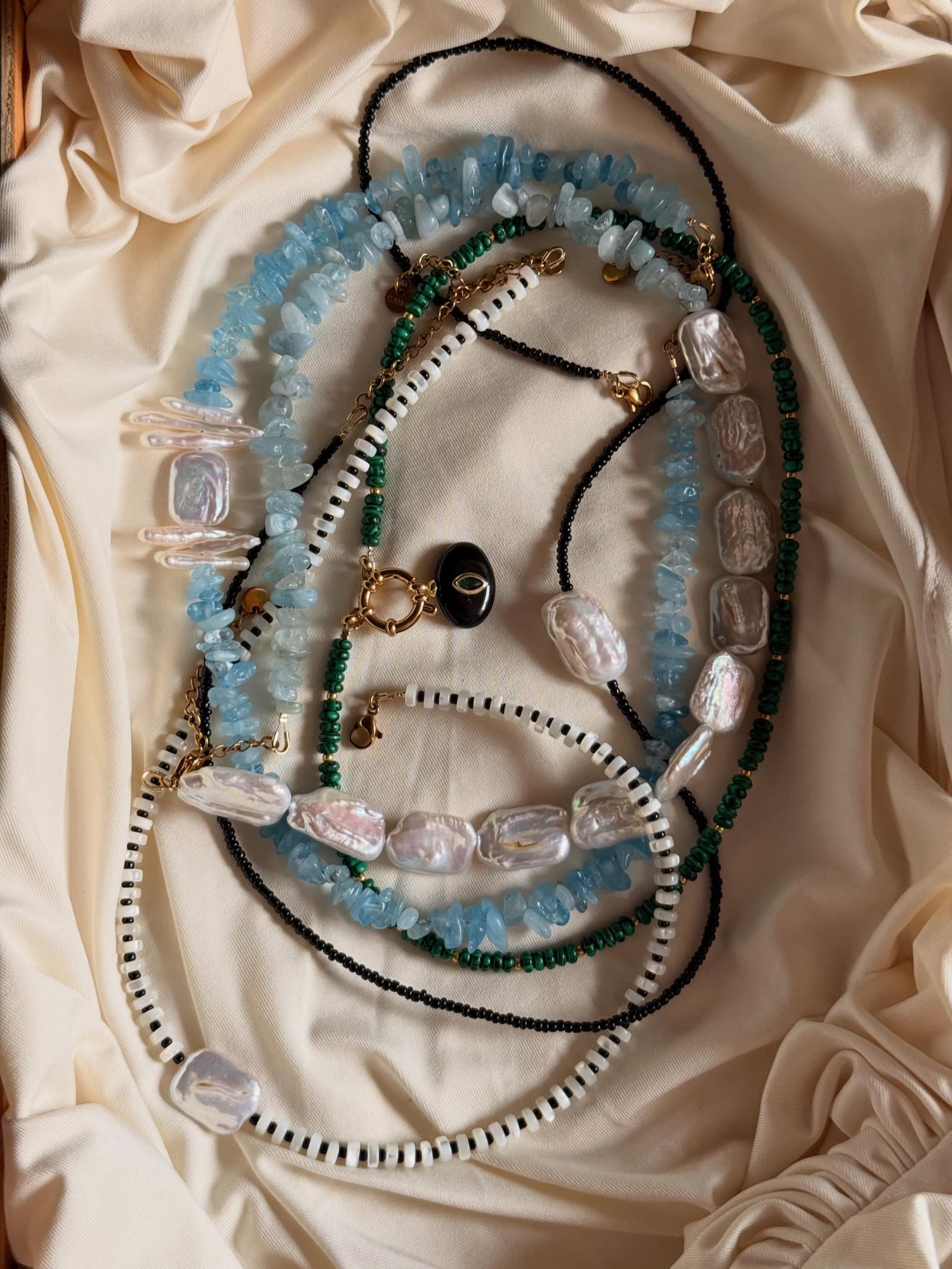 Bijoux en perles et pierres naturelles posés sur soie ivoire