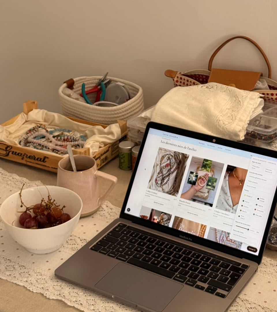 La table du studio : perles, mug de thé et le site Celia Stuudio sur l'ordinateur