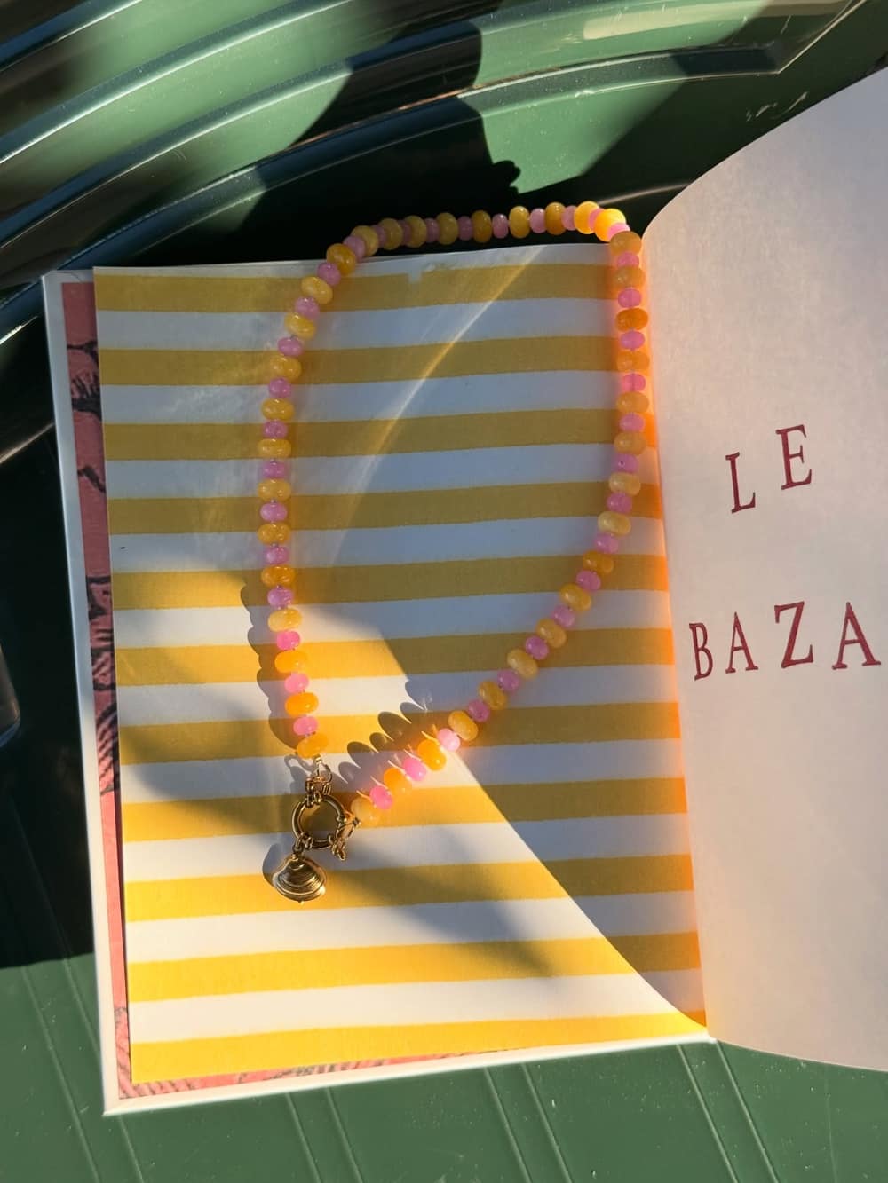 Collier en perles sur mesure posé sur un magazine